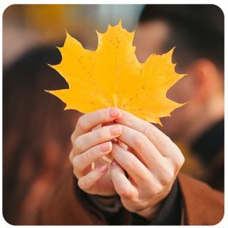 Paar mit Herbstblatt. Link zu unserem Onlineschaufenster Romantisch in den Herbst.